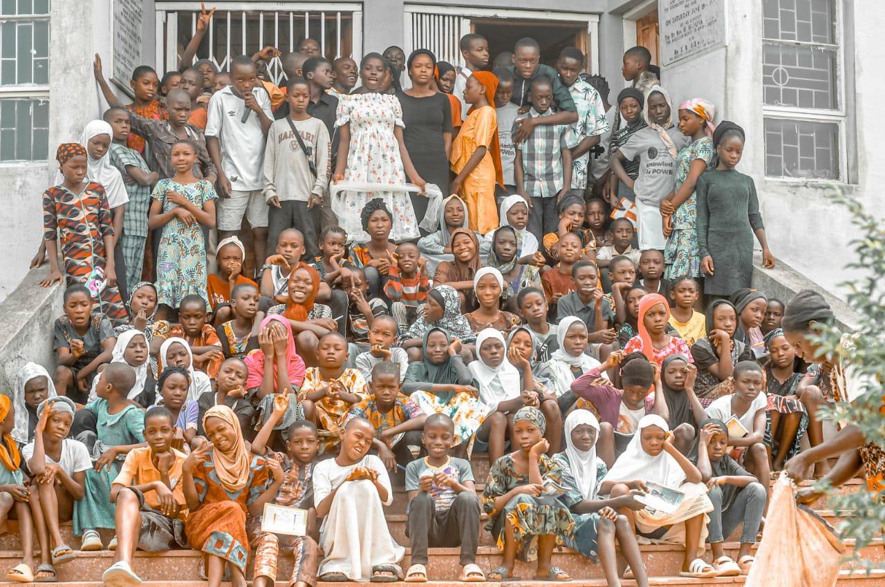 A large group of children and young people gathered on the steps of the David Folayan Memorial Library in Iludun-Oro.
